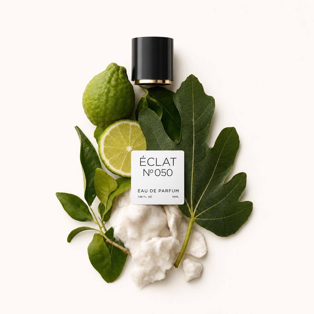 Ett arrangemang av citrusfrukter, gröna blad och mjuka vita fibrer, med en svart kork med ÉCLAT White Musk & Citrus Fruits etikett.