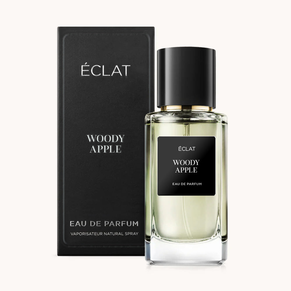 Un frasco de vidrio facetado de ÉCLAT Woody Apple con tapa negra, acompañado de su caja negra a juego.