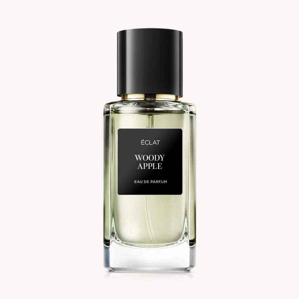 ÉCLAT Woody Apple en un frasco de vidrio facetado con etiqueta negra y tapa negra elegante.