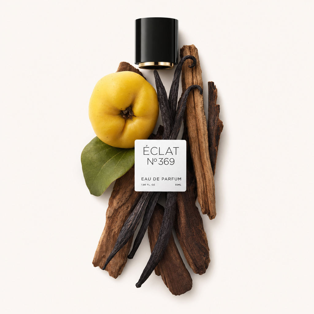 An arrangement of vanilla pods, a yellow quince with a green leaf, and wooden sticks around a black cap with a label from ÉCLAT Woody Vanilla.
